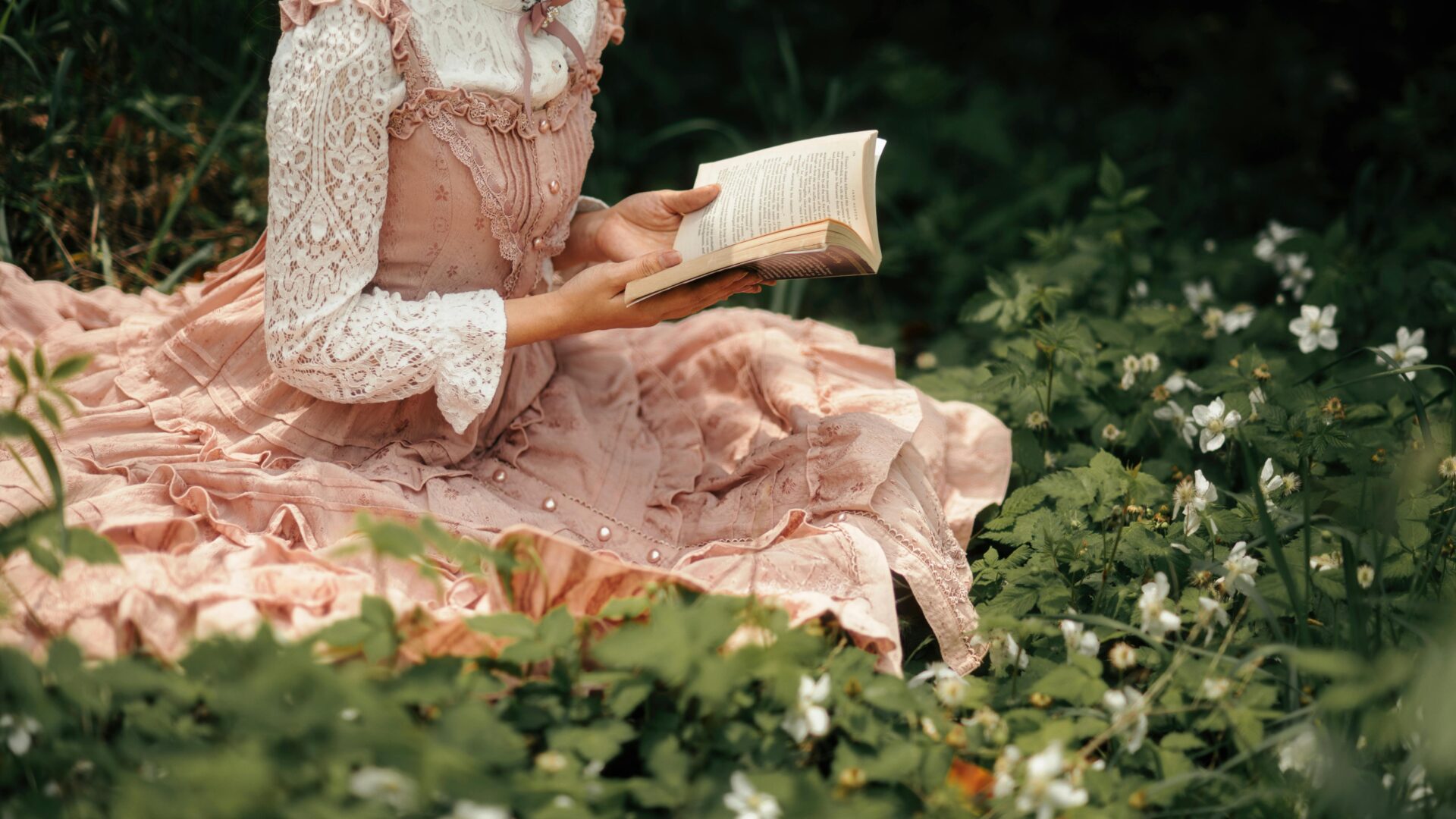 Frau im Spitzenkleid liest ein Buch zwischen FrÃ¼hlingsblumen auf einer Waldwiese.